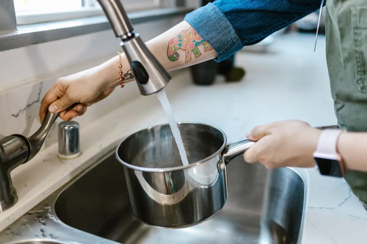 Filling a stainless steel saucepan with water at the sink