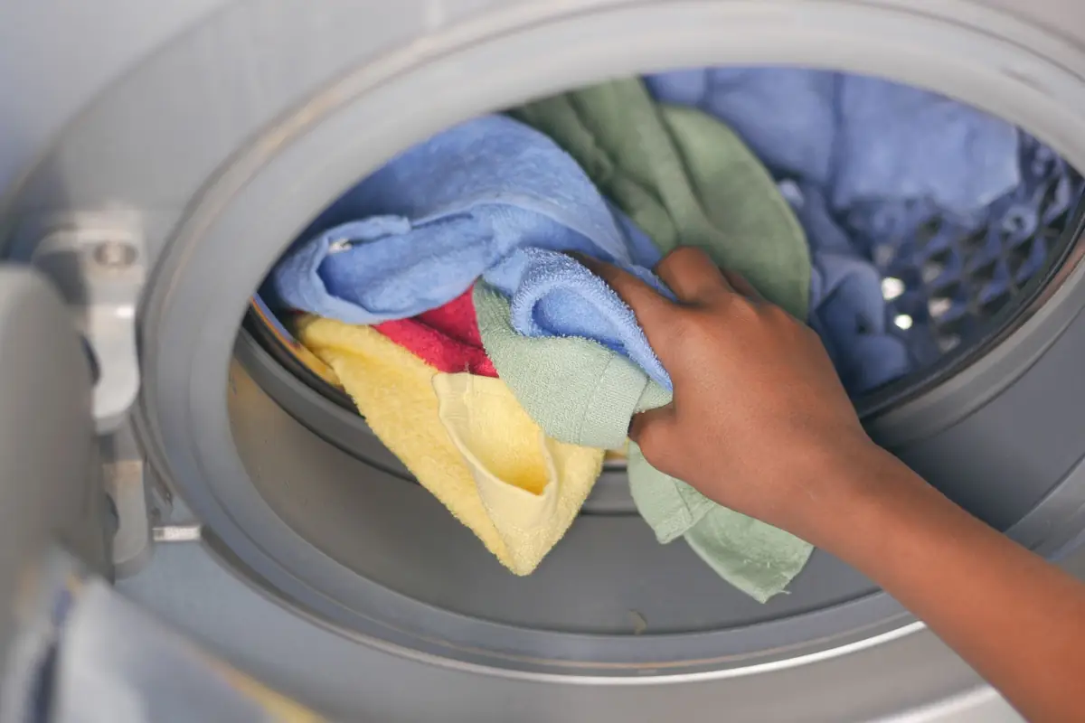 Colorful towels being loaded past the rubber door seal of a front-load washer
