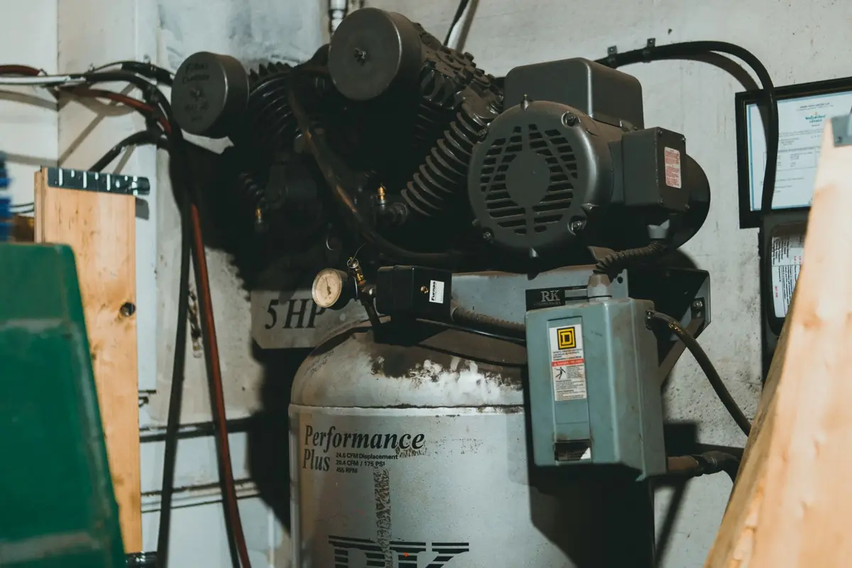 A belt-driven air compressor with a vertical tank in a workshop