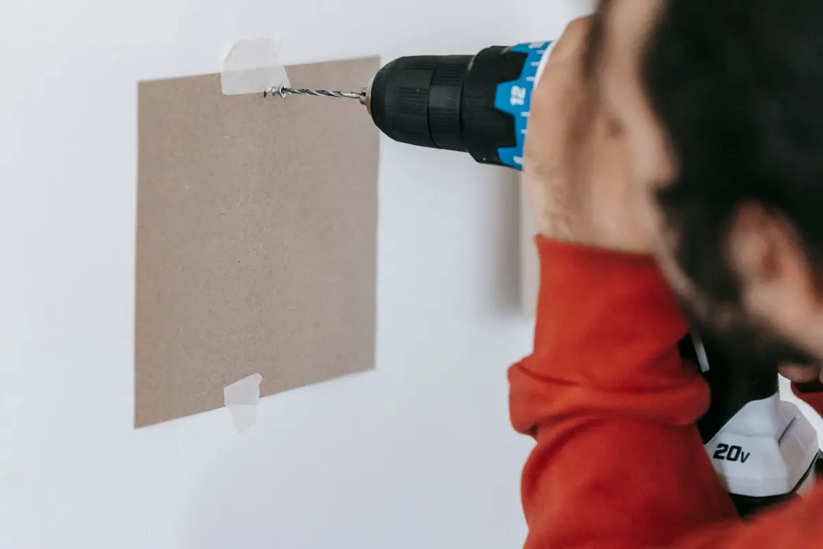 A man drilling a hole in a wall with a cordless drill
