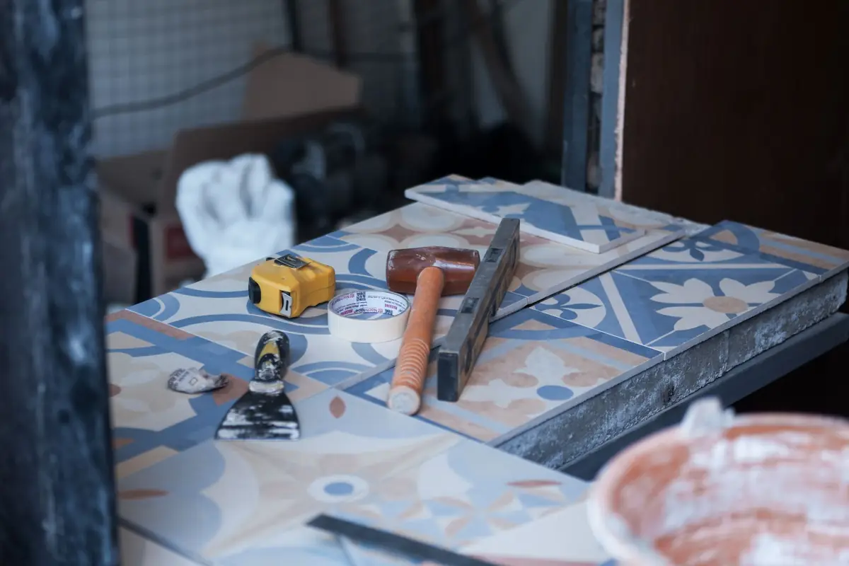 A hammer, trowel and tape measure resting on patterned floor tile