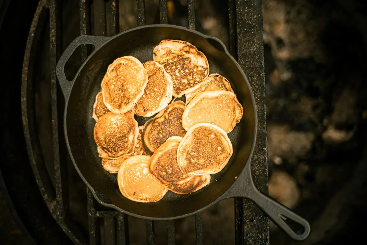 Small pancakes cooking in a cast iron skillet