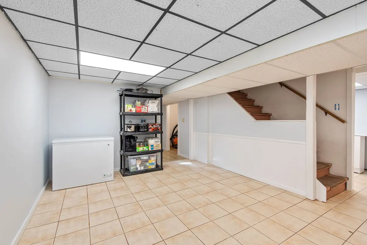 A finished basement with a tile floor, storage shelves and stairs