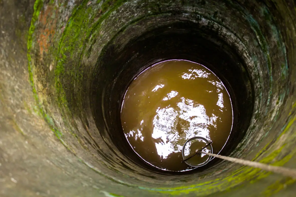 Looking down an old stone well at the water below