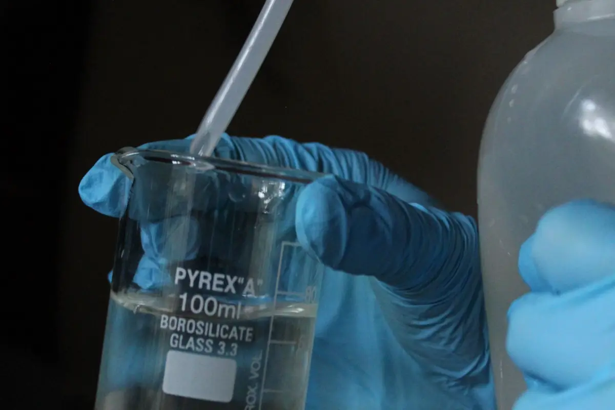 Gloved hands holding a water sample in a lab beaker