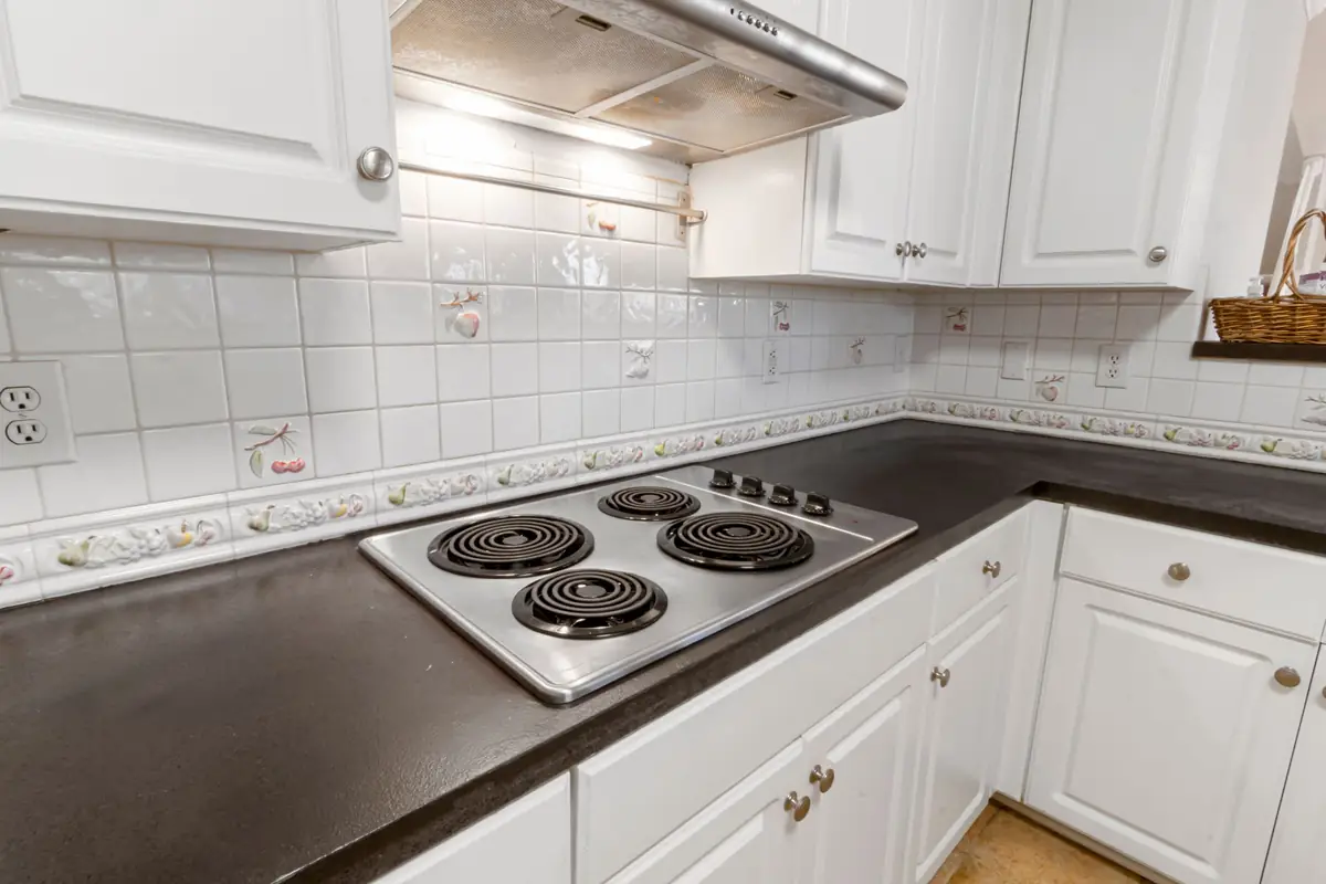A white kitchen with a coil electric stove top