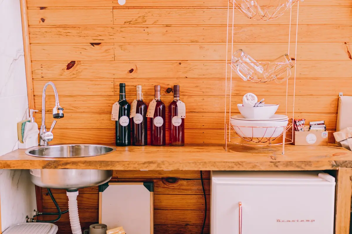 A wood-paneled kitchenette with a small sink and a mini fridge under the counter