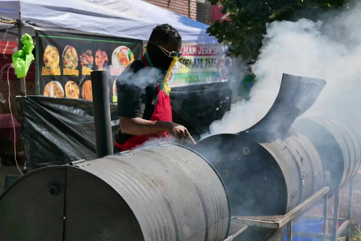 A cook tending a large barrel smoker at a food festival