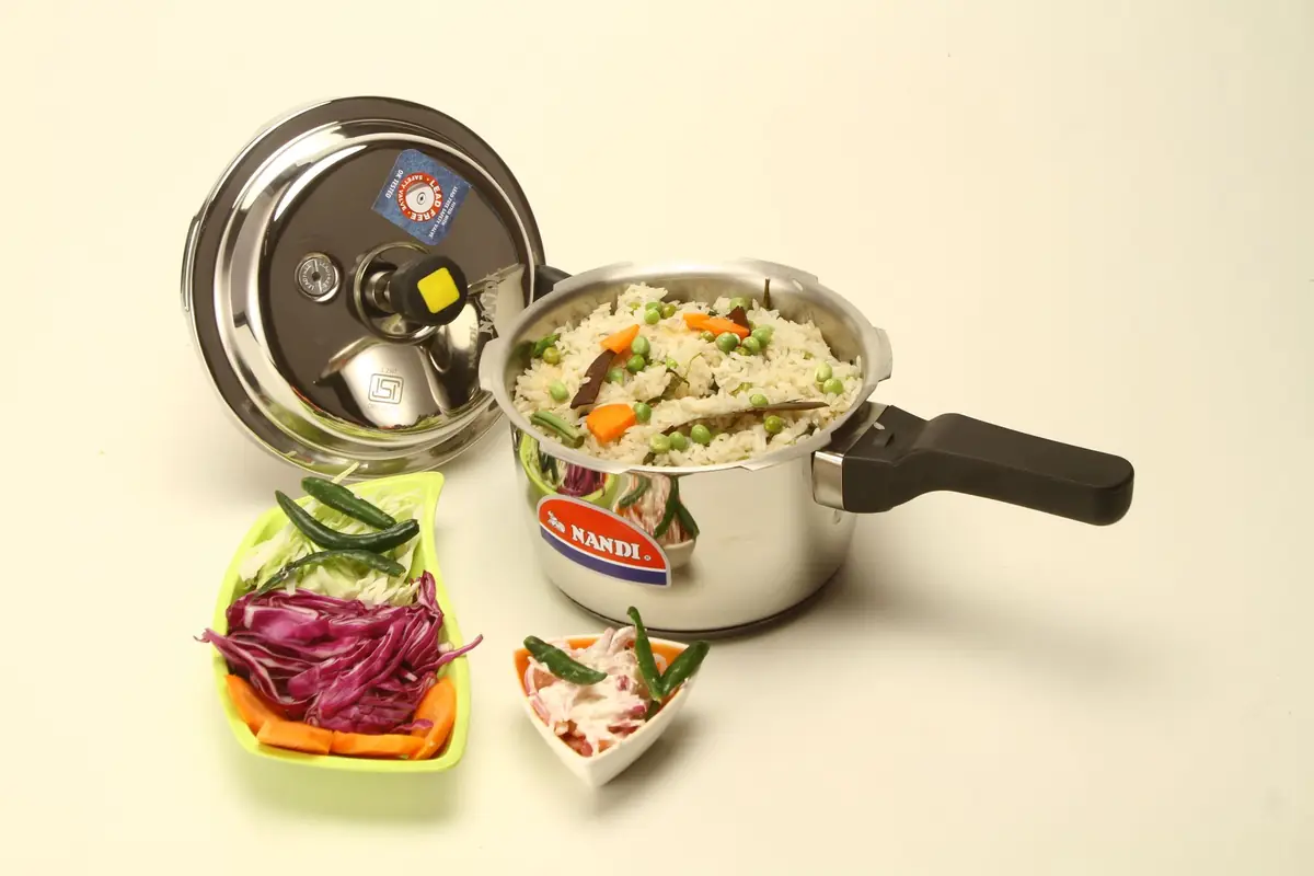 A small stainless pressure cooker filled with cooked rice and vegetables