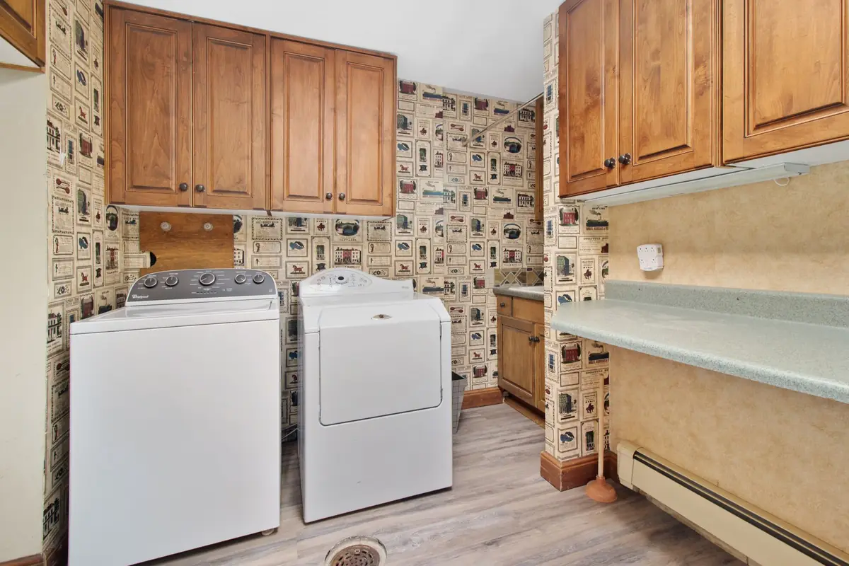 A washer and dryer side by side under wooden cabinets in a laundry room