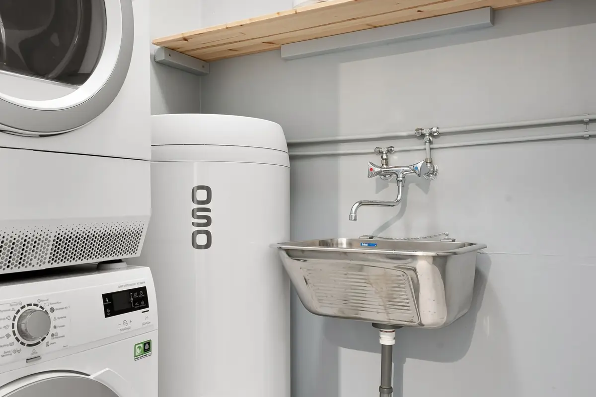 A compact laundry space with a stacked washer and dryer and a utility sink