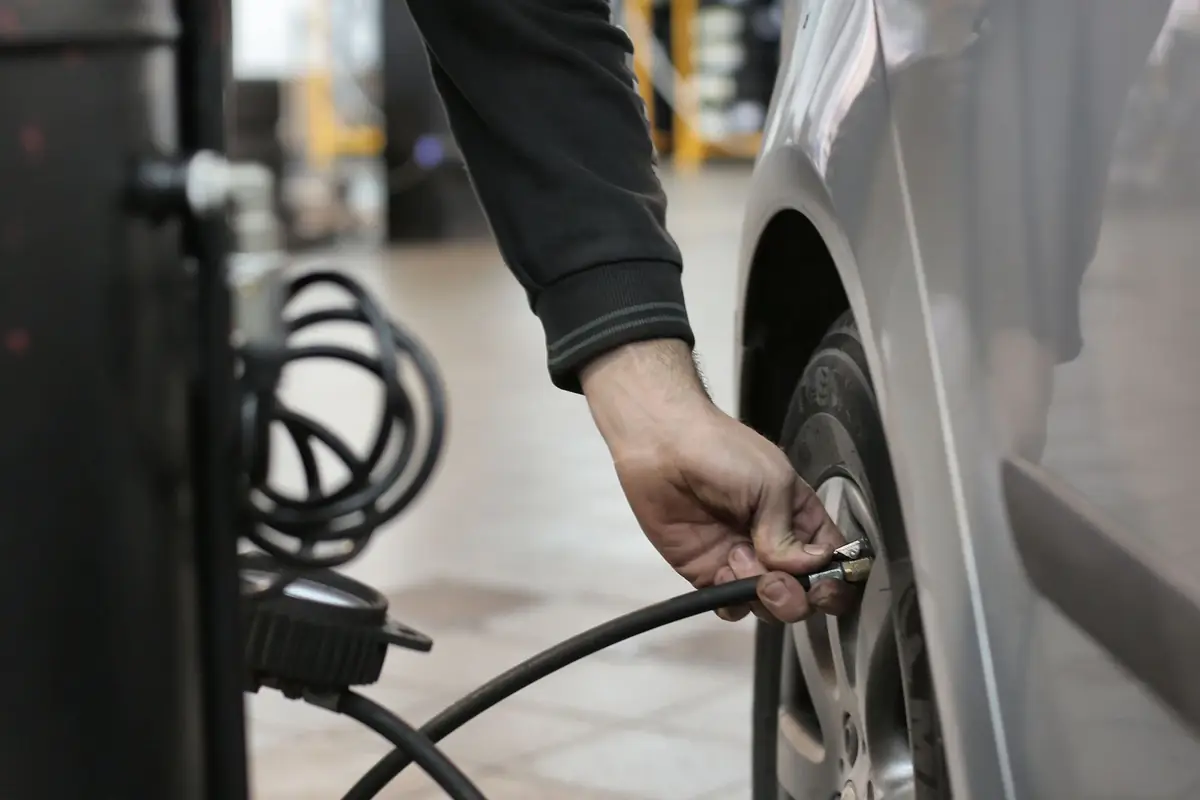 A hand connecting an air hose to a car tire valve