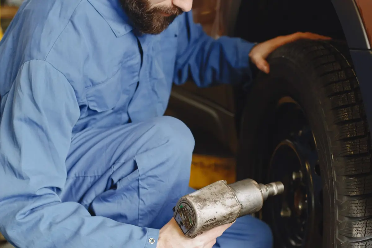A mechanic using an air impact wrench on a car wheel