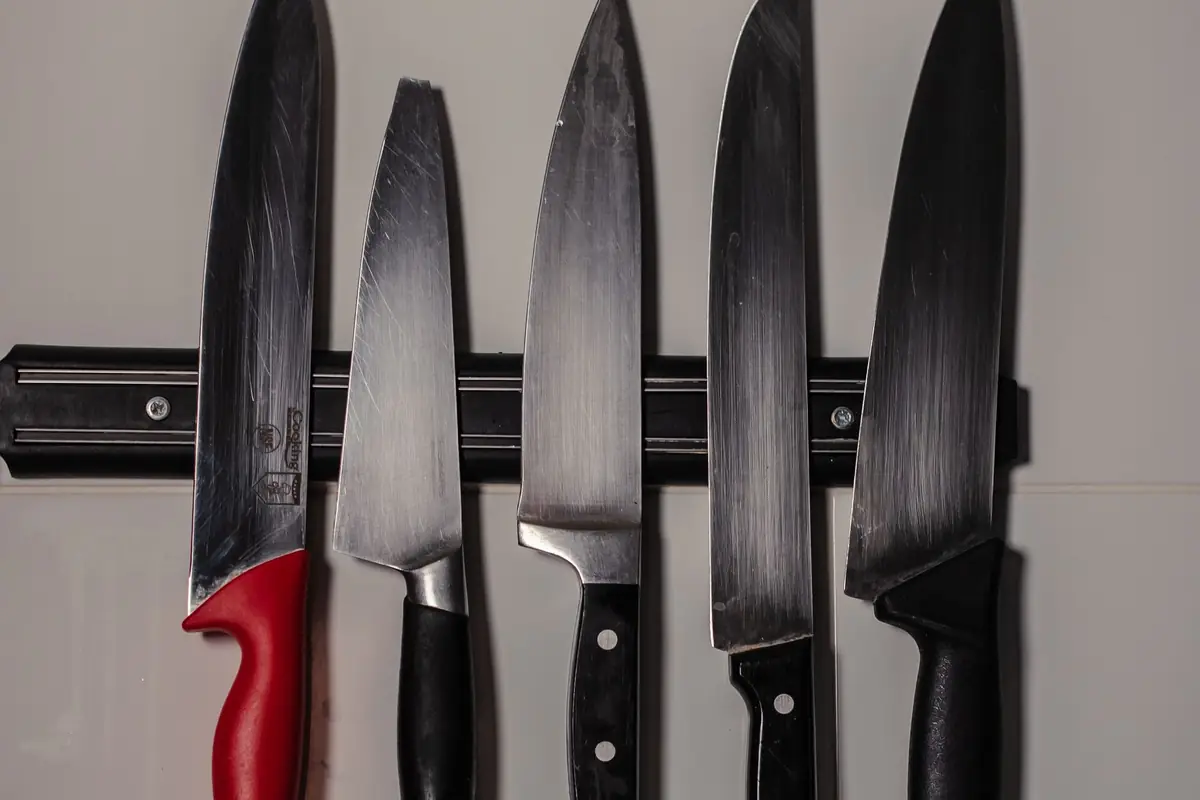 Five kitchen knives hanging on a magnetic strip